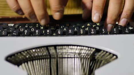 close up over the top view of typist using vintage typewriter focus on typist's fingers