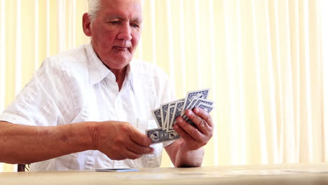 Senior-man-sitting-at-table-playing-solitaire