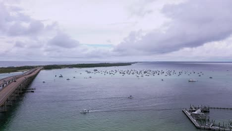 Aerial-view-flying-down-the-side-of-the-Destin-FL-bridge-towards-all-the-boats-at-Crab-Island