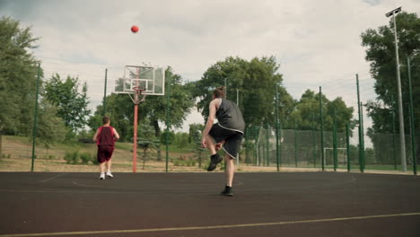 two male basketball players training together in an outdoor basketball court