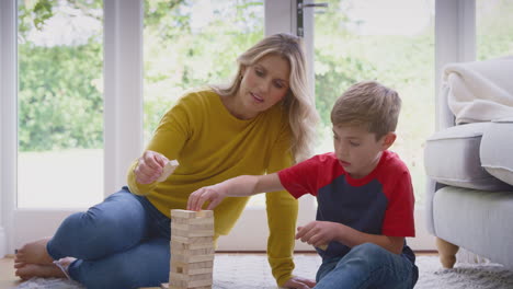 mother and son at home playing game stacking and balancing wooden blocks together