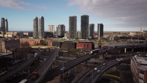 toma panorámica aérea del tráfico en la intersección de la autopista en el distrito de puerto madero de buenos aires durante el día - horizonte con rascacielos en segundo plano