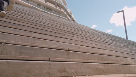 A-girl-is-running-up-wooden-stairs-in-a-city-during-a-sunny-day