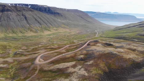 Luftaufnahme-Eines-Weißen-Autos,-Das-Bergauf-über-Schotterstraßen-In-Der-Wunderschönen-Natur-Islands-Fährt