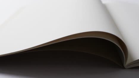 close up of open blank book with copy space on white background in slow motion