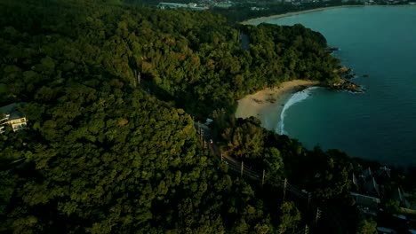 4K-Cinematic-nature-aerial-footage-of-a-drone-flying-over-the-beautiful-beach-of-Surin-in-Phuket,-Thailand-during-sunset