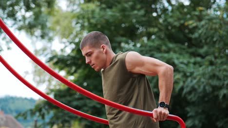 man trains push-ups on training device in public park monitoring training session with smartwatch