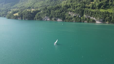 Escena-Relajante-De-Un-Yate-En-Solitario-Navegando-En-Aguas-Tranquilas-De-Un-Lago-Turquesa,-Capturada-Por-Un-Dron