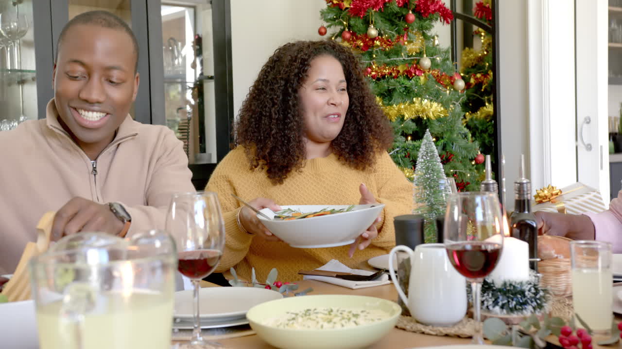 feliz madre afroamericana sirviendo comida en la mesa de la cena de navidad de la familia de varias generaciones
