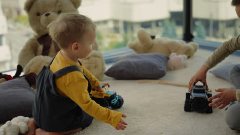 beautiful siblings playing with toys at home. nice brothers sitting carpet