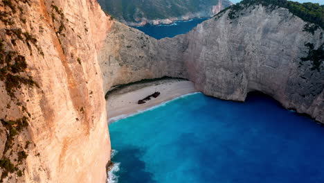 Imágenes-Cinematográficas-De-Drones-De-La-Playa-Del-Naufragio-En-La-Playa-De-Navagio,-Que-Muestran-Los-Espectaculares-Acantilados-Y-Las-Aguas-Cristalinas.