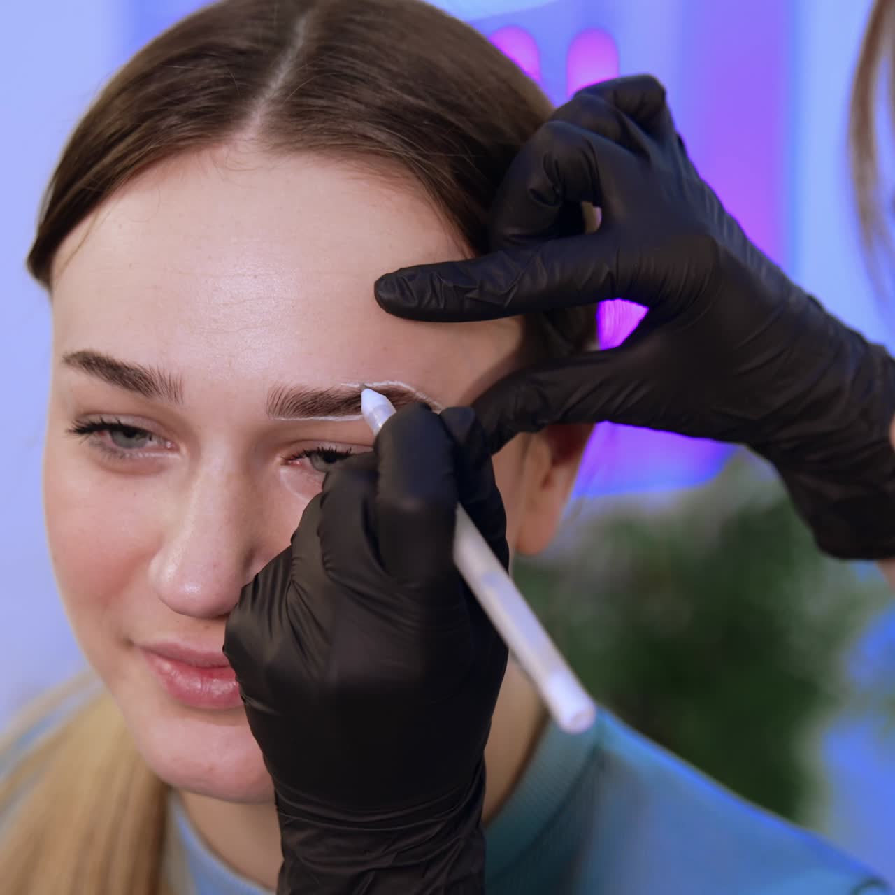 Salon brow master applying white marks around girl's eyebrows. Preparatory process for eyebrow make up. Close up