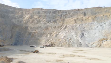 Aerial-view-of-heavy-machinery-working-at-a-quarry-site,-sunny-day