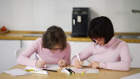 two girls draw with colorful pens at home