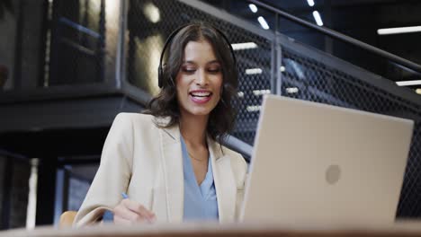 Happy-biracial-casual-businesswoman-making-video-call-using-laptop-in-office-lounge,-slow-motion