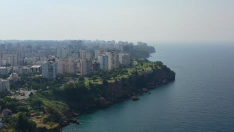 Drone-Aéreo-Que-Revela-El-Horizonte-De-Antalya-Turquía-En-Una-Tarde-De-Verano-Con-Grandes-Acantilados-Rodeados-Por-El-Mar-Mediterráneo