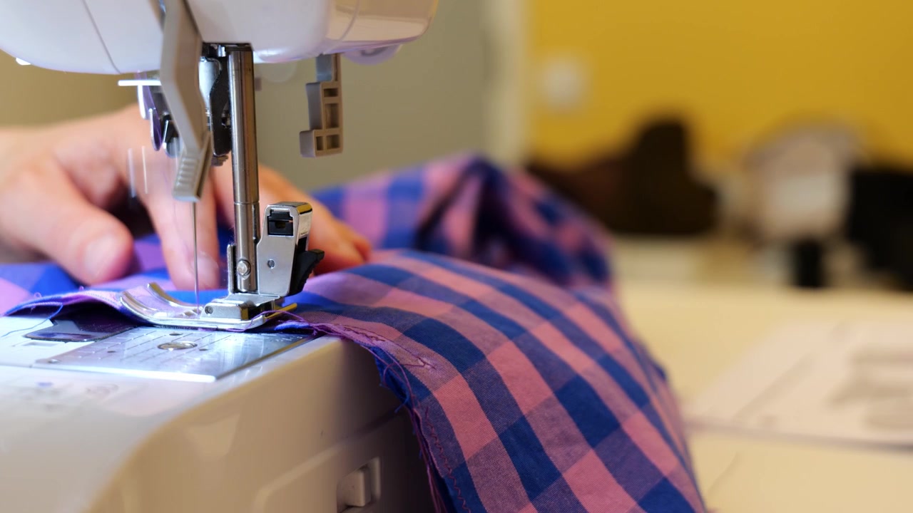 Close Up Tailor Hands Operating Modern Sewing Machine Stitching Fabric Cloth.