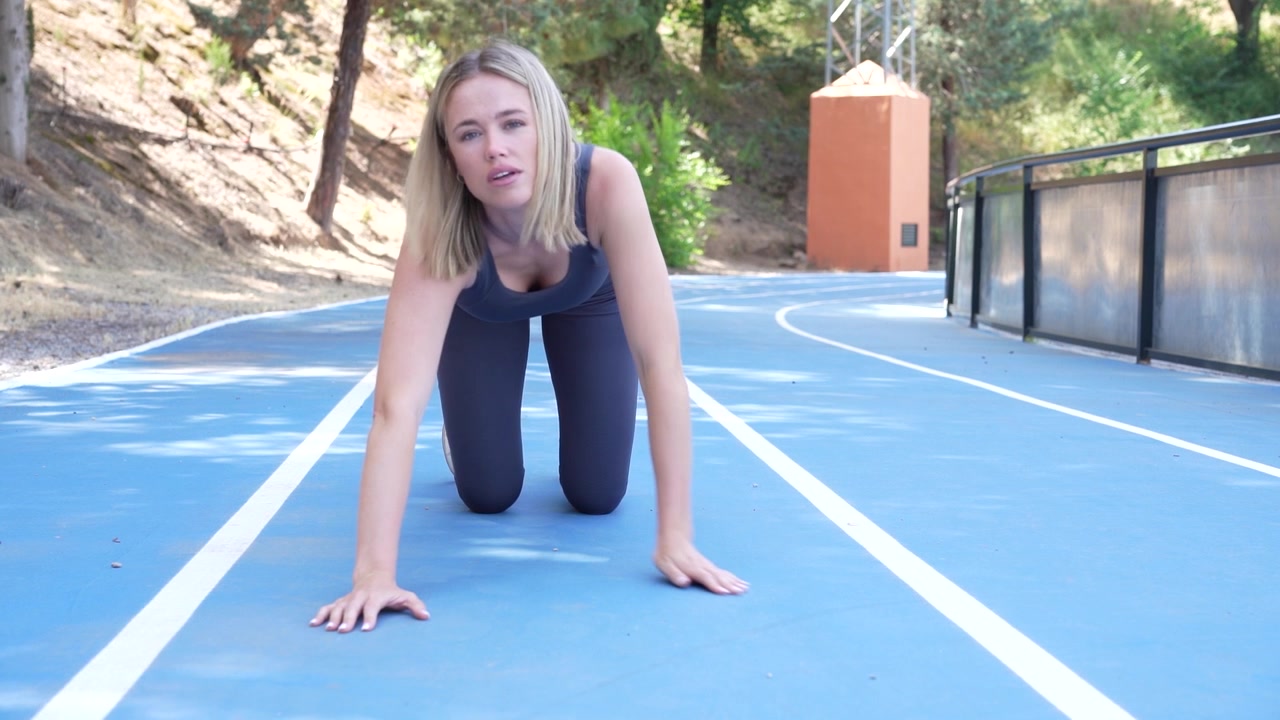 Uma mulher demonstra comprometimento e determinação fazendo flexões em uma pista como parte de sua rotina de treino.