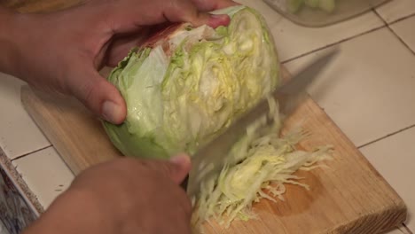 hands shredding a lettuce on a cutting board