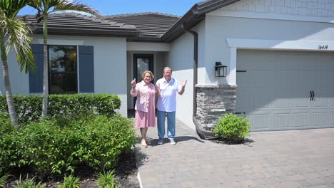 satisfied home owner customers give the thumbs up symbol in front of their home