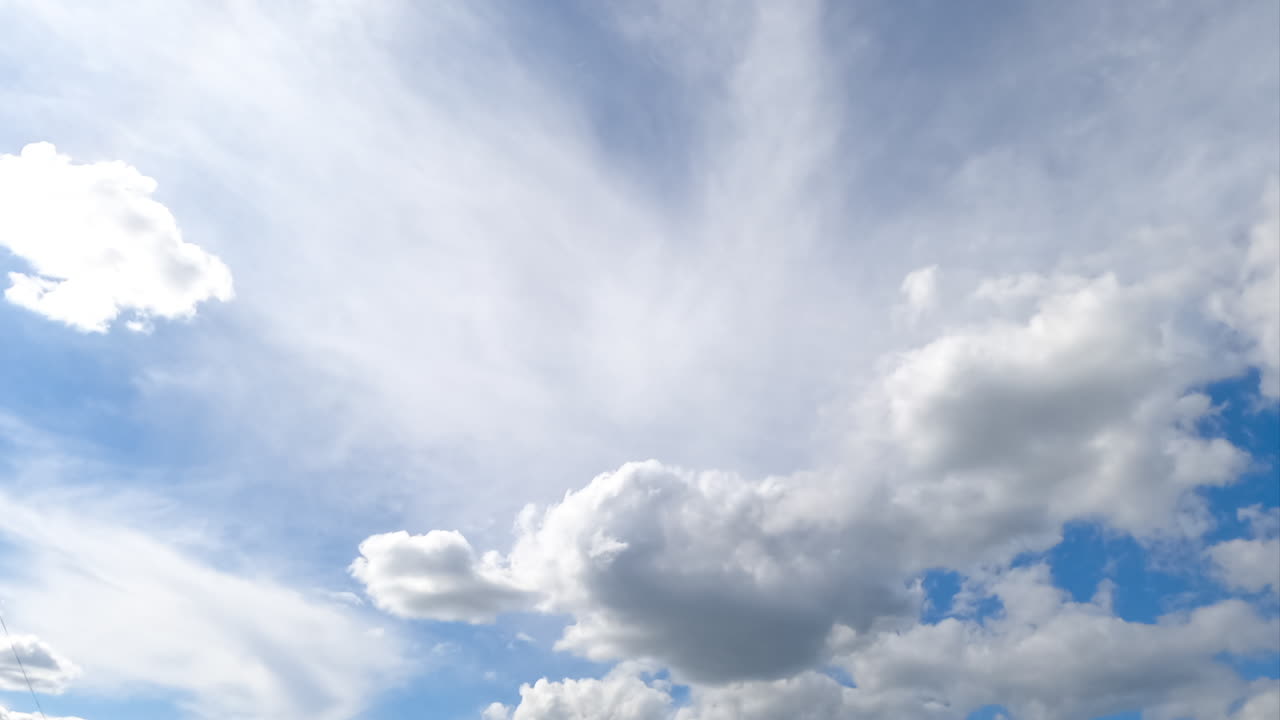 Cumulus and spindrift clouds transformation in the summer sky. Low angle view on the blue skies with multiple clouds. Timelapse.
