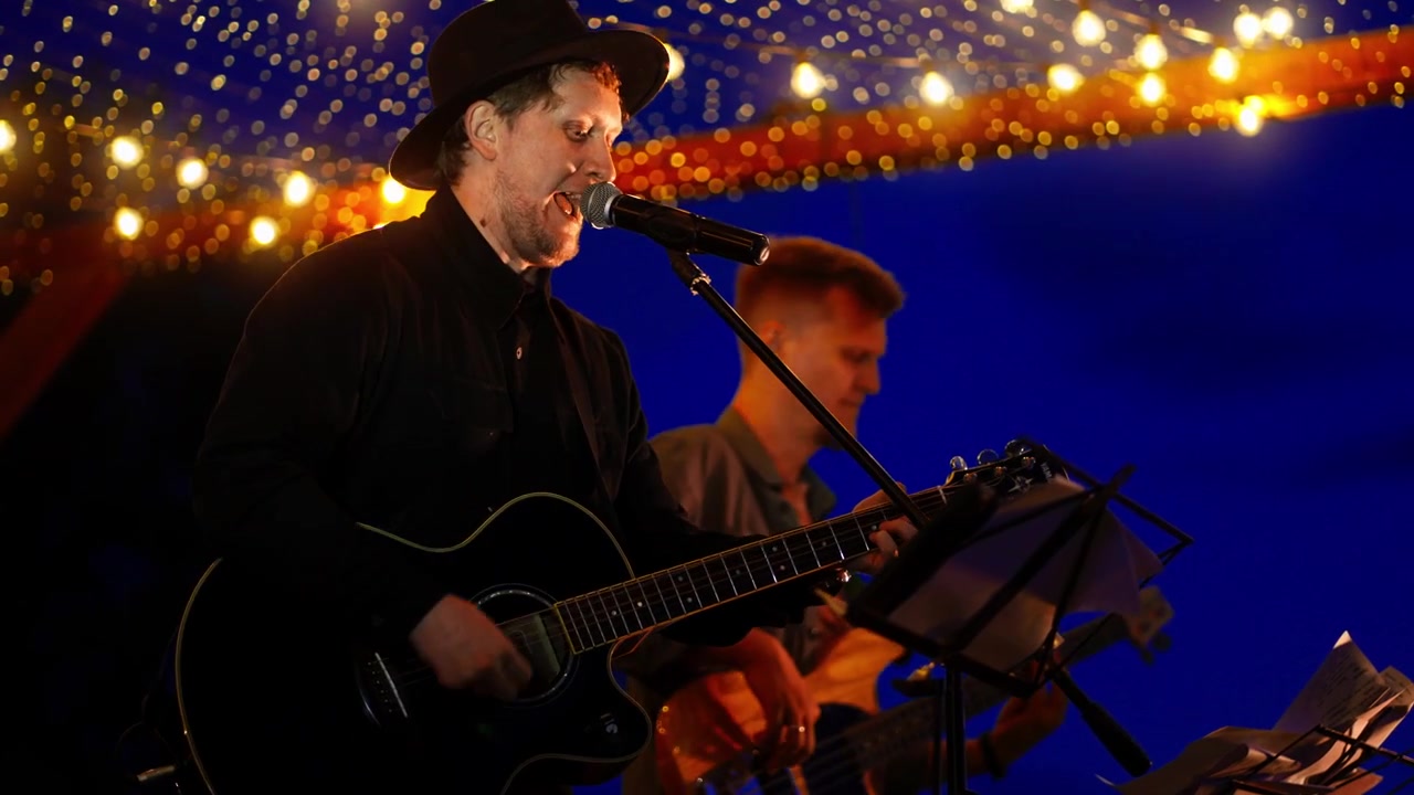Mandlig musiker synger og spiller akustisk guitar på scenen