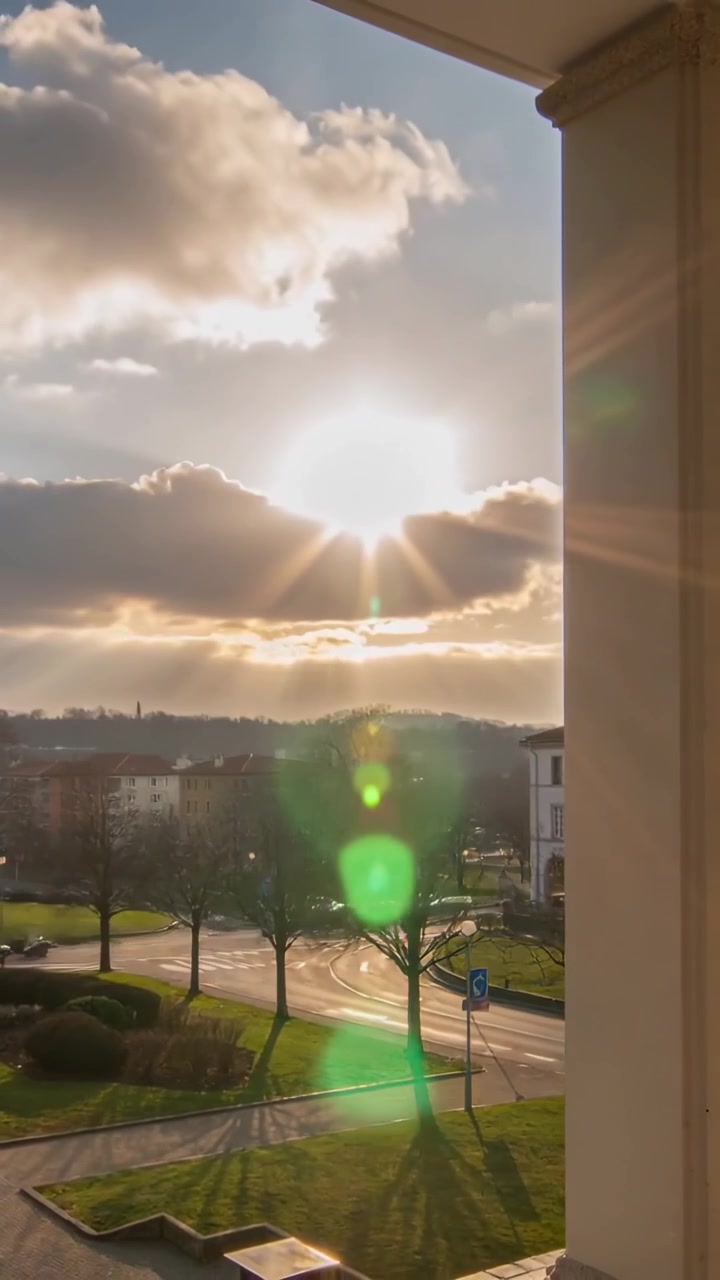 Vídeo vertical: Banco de nuvens em movimento flutuando sobre o sol, diminuindo o brilho e com reflexos verdes da varanda