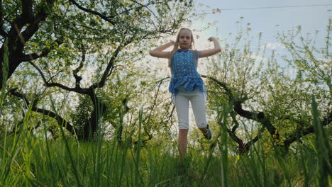 funny girl dances in the apple orchard in the sun