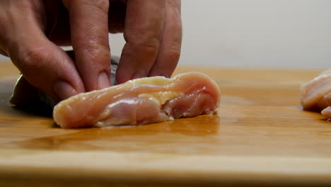 Hand-slices-raw-chicken-into-strips