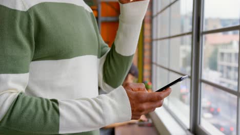 hombre de negocios bebiendo café mientras usa el teléfono móvil en la oficina 4k