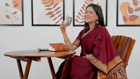 rich indian woman using money as fan