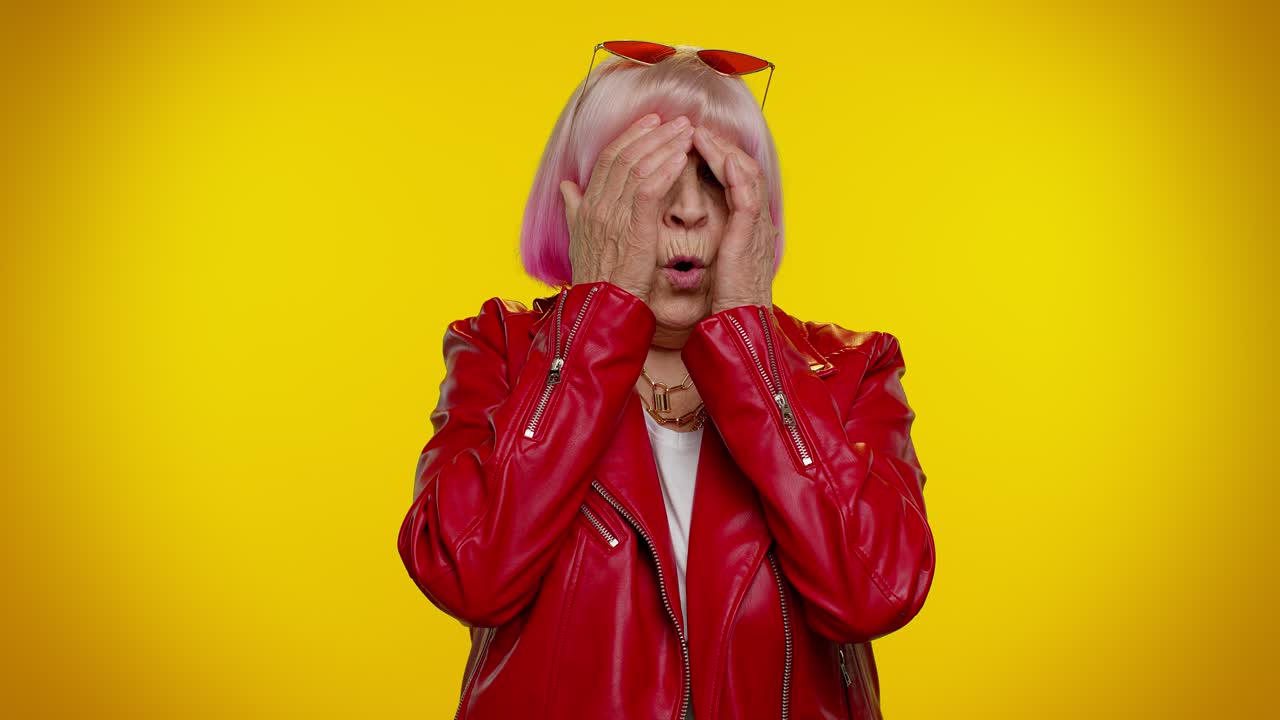 una mujer con cabello rosa y chaqueta de cuero roja se sorprende.