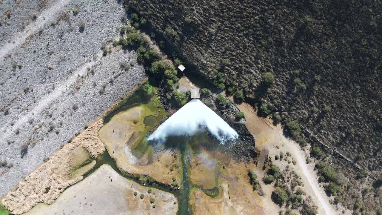 vista de arriba hacia abajo de un avión no tripulado de un vertedero que arroja poderosamente agua, capturando la fuerza dinámica del flujo y la escena dramática del agua que se precipita desde la presa