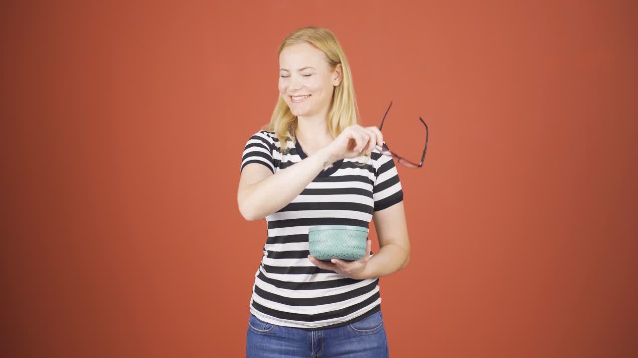 una mujer sin problemas de visión tira gafas a la basura.