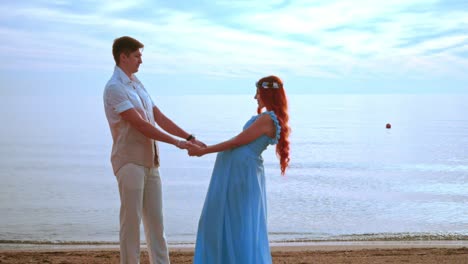 young people holding hands on sea beach. pregnant couple beach