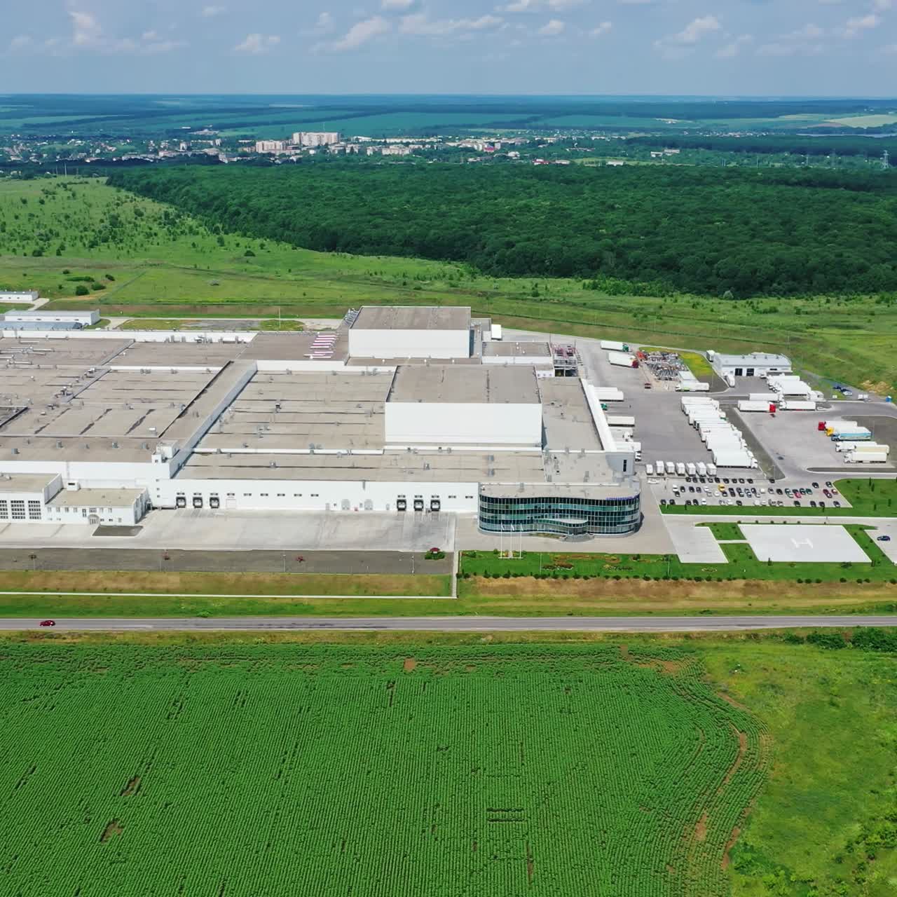 Production plant among green nature. Industrial complex near the road in the countryside. Aerial view.