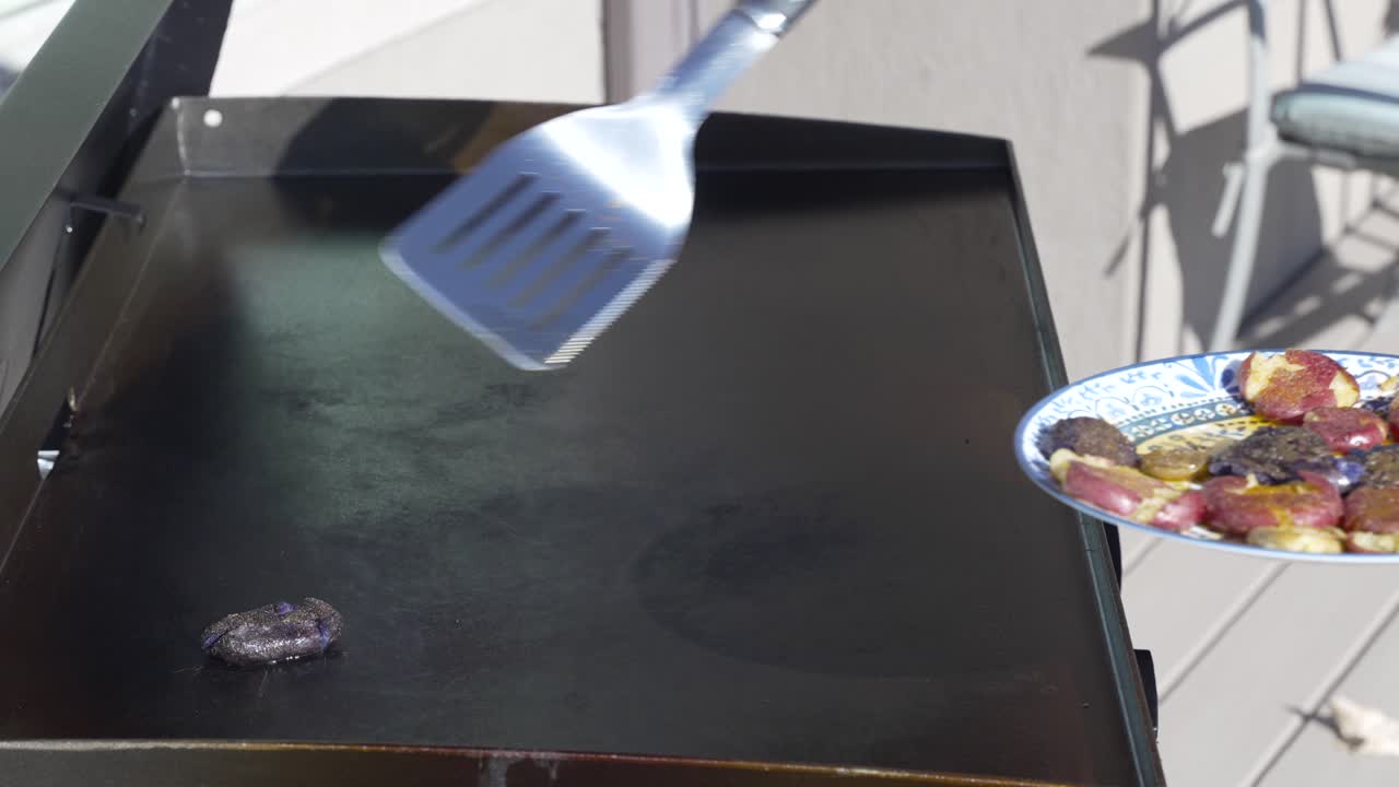 Putting smashed potatoes on the flat top griddle to fry for breakfast