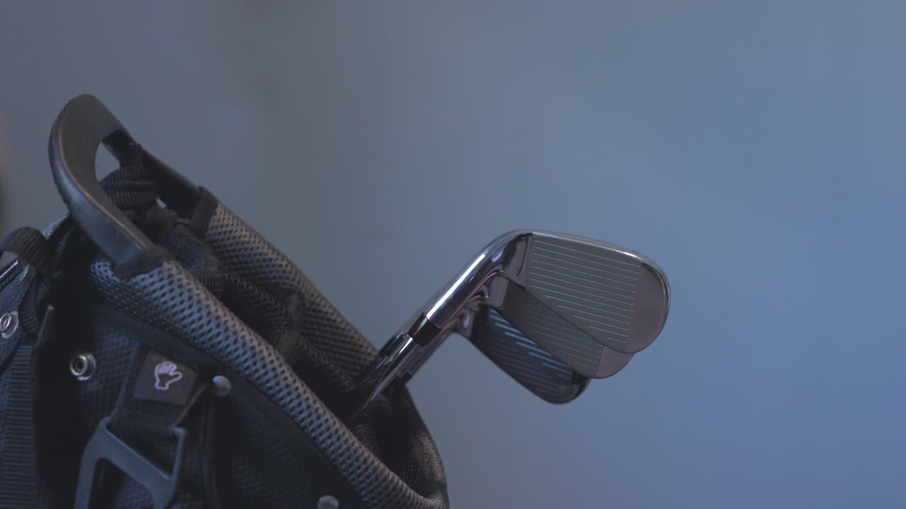 golfer placing multiple golf clubs back into his bag after a shot