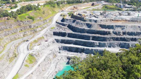 aerial footage of a tiered quarry in gold coast, australia, showcasing mining activity under bright daylight