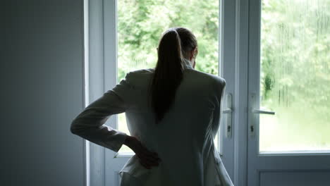 a silhouette of a pensive woman looking out of a window stressed