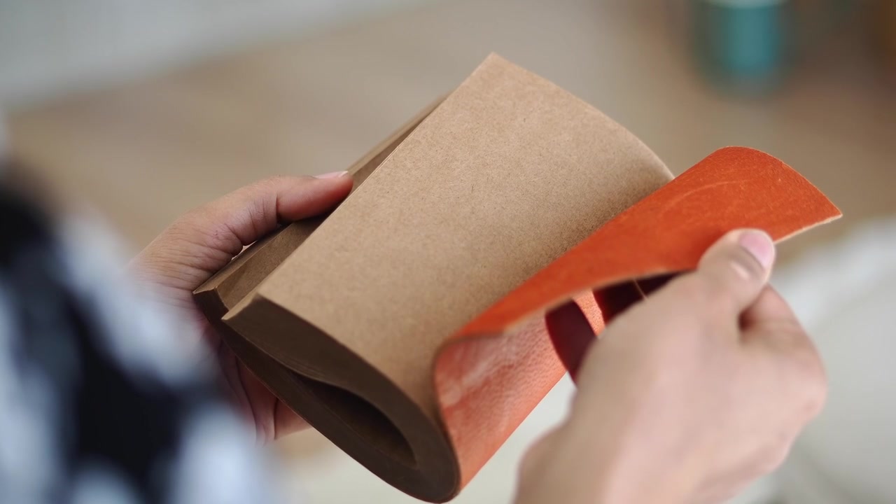 Close-up of Hands Flipping Through Pages of a Kraft Paper Notebook
