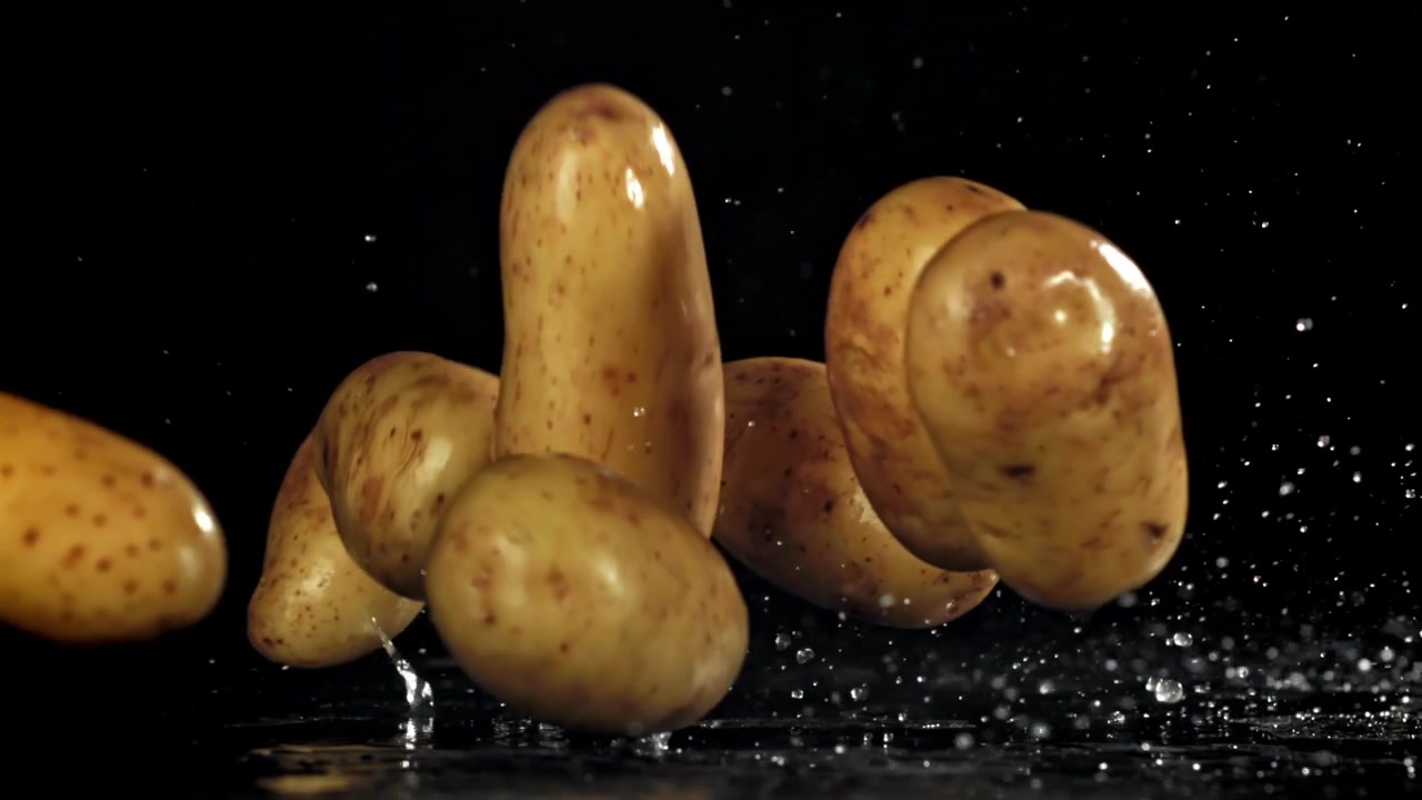 Patate fresche che cadono e schizzano nell'acqua su sfondo nero