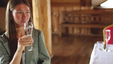 young attractive woman picking up a glass of champagne and drinks it in a lovely environment