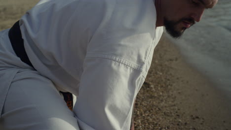 Sporty-man-stretching-training-on-beach-closeup.-Active-athlete-training-balance