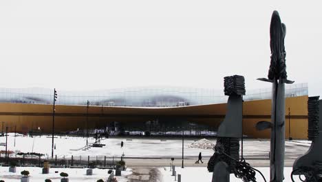la biblioteca central de helsinki cubierta de nieve oodi, arquitectura moderna, día de invierno, estatuas en primer plano