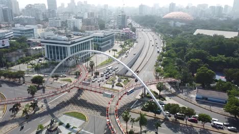 drone shot with 180 degrees movement of pedestrian bridge with view of buildings in the background, sunny weather in santo domingo