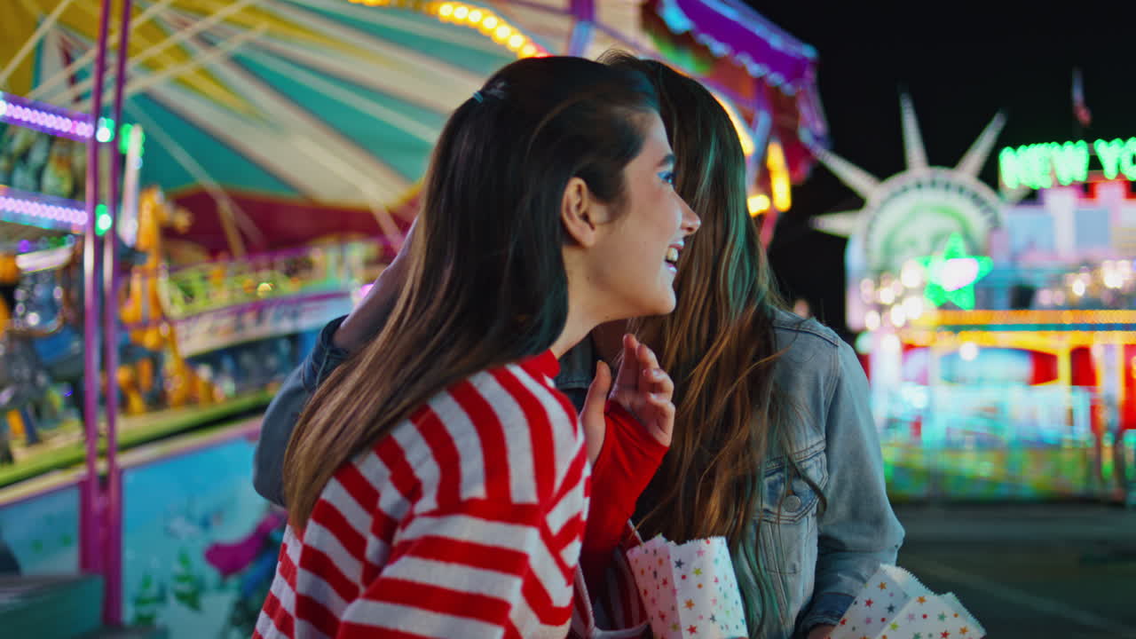 Joyful girls talking sharing secrets at luna amusement park. Happy best friends