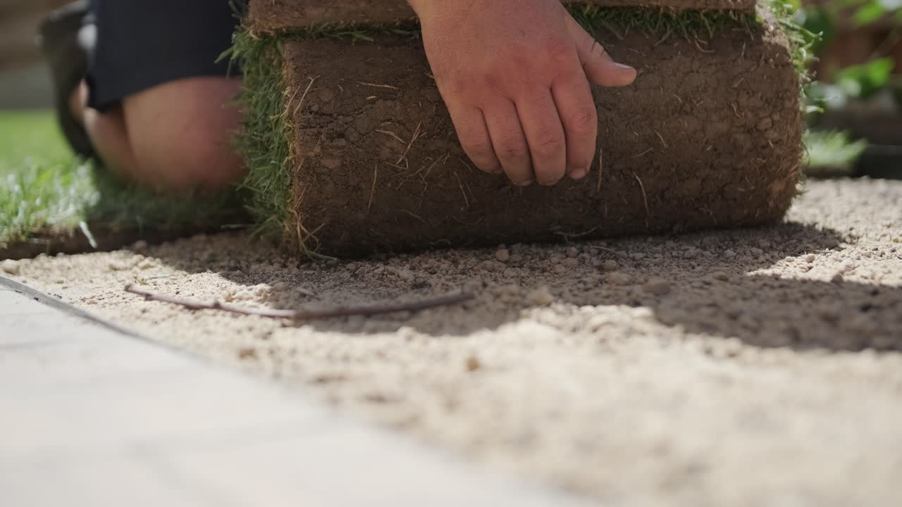 jardinero colocando césped en el patio privado con valla de madera