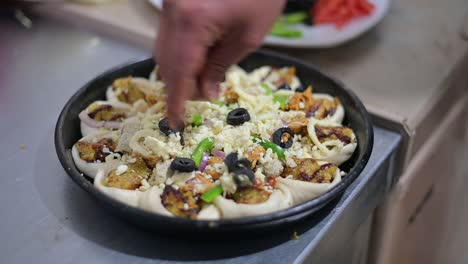 Cubriendo-La-Pizza-Con-Aceitunas-Frescas-Y-Tomate