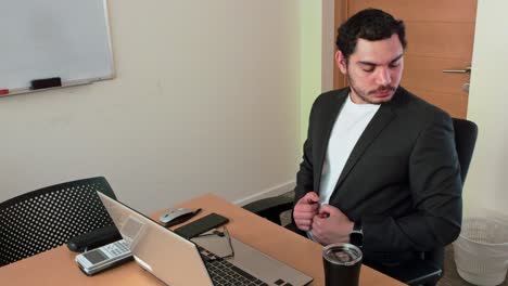 a man is sitting at a desk with a laptop and a cup of coffee
